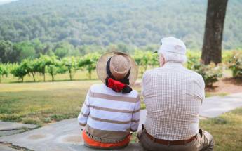 Zwei ältere Menschen sitzen im Grünen und genießen die Aussicht