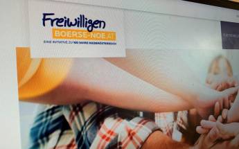 Auf einem Computerbildschirm ist das Logo der Freiwilligenbörse Niederösterreich abgebildet. Darunter halten Menschen ihre Hände zusammen.
